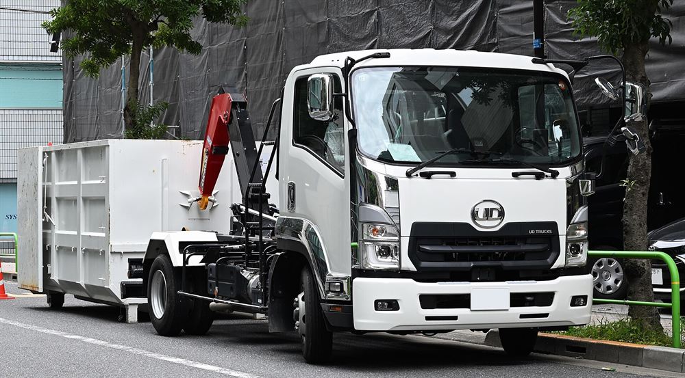 Roll-off truck placing a dumpster on a driveway