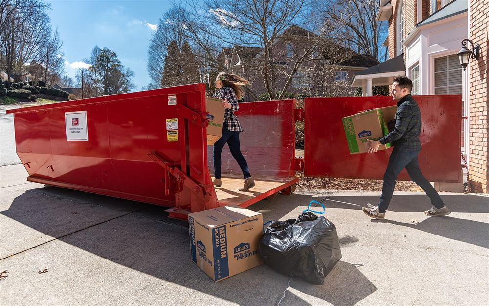Moving boxes and furniture next to a dumpster